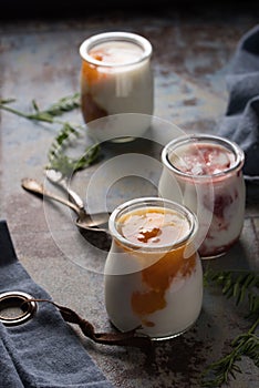 Three portions of fresh natural homemade organic yogurt in a glass jar on a vintage background