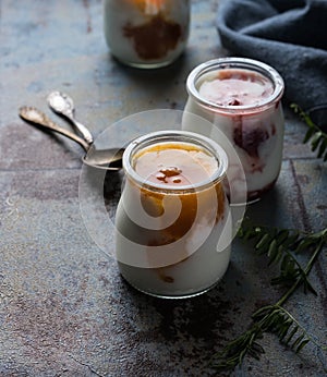 Three portions of fresh natural homemade organic yogurt in a glass jar on a vintage background