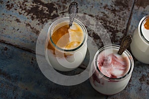 Three portions of fresh natural homemade organic yogurt in a glass jar on a vintage background