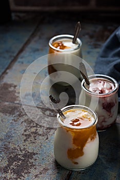 Three portions of fresh natural homemade organic yogurt in a glass jar on a vintage background