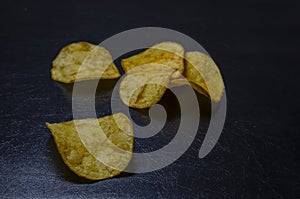 Three potato chips on a black background