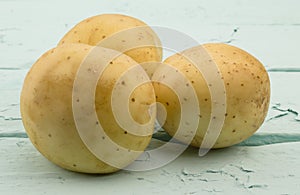 Three potatoes on sea green wood