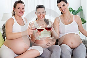 Three pregnant women drinking wine