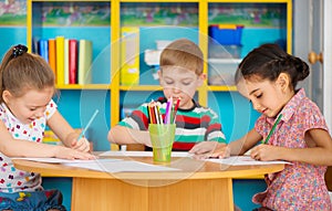 Three preschool children drawing at daycare