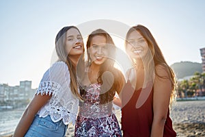 Three pretty girls standing on beach in sunlight
