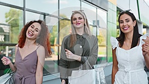 Three pretty shopper girl smiling dancing walking outdoor at window glass background