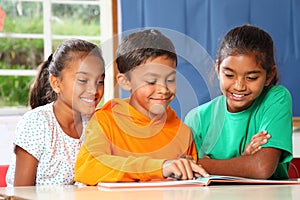 Three primary school children reading and learning