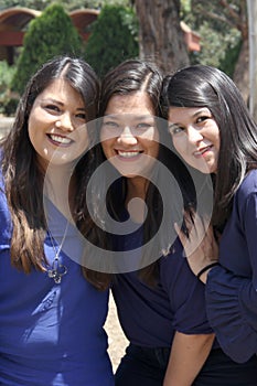Three professional, accomplished, confident, empowered, strong Latin women sisters with straight hair dressed in blue are in a par