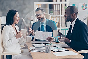 Three professional, successful, stylish, elegant employees having break time during conference, speaking, drinking tea holding mu