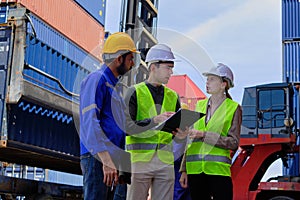 Three professional workers team at logistics crane with stacks of containers