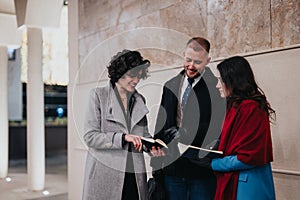 Three professionals in winter attire having a friendly discussion outdoors.