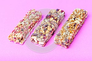 Three protein bars with cereals and useful trace elements isolated on pink background