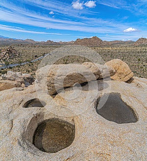 Three puddles on the rock with a view of a rocky mountains at Joshua Tree National Park, California