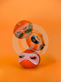 Three pumpkin with eye patches, facial mask and towel on orange background