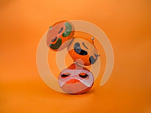 Three pumpkin with eye patches, facial mask and towel on orange background