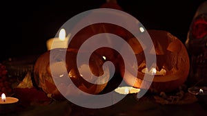 Three pumpkins with faces on Halloween with candles inside flickering in dark