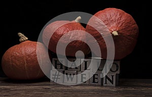 Three pumpkins on wooden cubes Halloween on dark wood