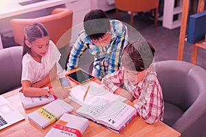 Three pupils poring over books in the classroom.