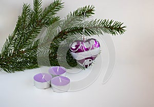 Three purple candles, a Christmas tree toy purple heart and green fir branches symbolize Christmas and New Year. Place