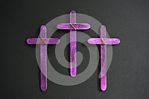 Three purple wooden cross in black background. Christian faith, holy week or lent season celebration concept.