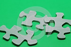 Three puzzle pieces in wood on green background