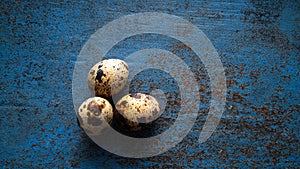 Three Quail eggs on a blue rustic metal bckground