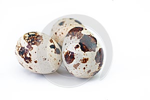 Three quail eggs over white background