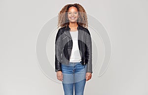 Three Quarter Length Studio Shot Of Happy Young Woman Wearing Leather Jacket Smiling At Camera