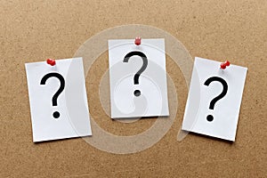 Three question marks pinned on a wooden board