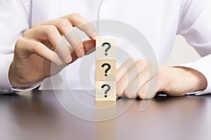 three question symbol on wooden cube blocks in businessman hands, man in white shirt