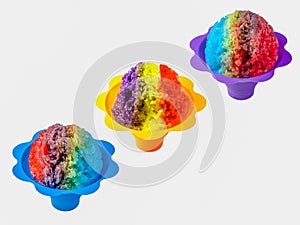 Three rainbow Hawaiian shave ice, shaved ice or snow cone desserts in a row against a white background. photo