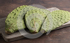 Three Raw Cactus Paddles on a Dark Wooden Table