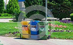 Three recycle containers for glass, plastic and paper on a city street