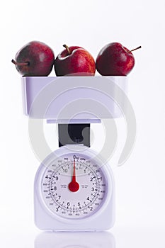 Three red apples on weighing scales