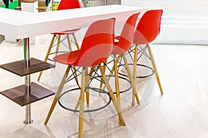 Three red bar stools on wooden legs close up