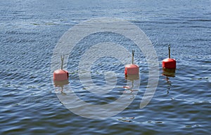 Three red buoys in blue summer sea.