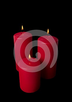 Three red candles burning isolated on black background