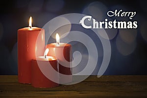 Three red candles with Merry Christmas text