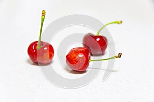 Three red cherries on white