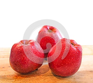 Red delicious apples on wooden table isolated on white background
