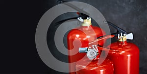 Three red fire extinguishers on a dark background