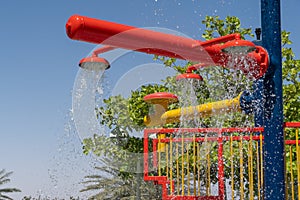 Three red fountain spray water park sprinklers spraying water above for children`s summer fun