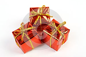 Three red glossy gift boxes with gold bow on white background