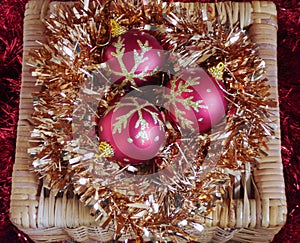 Three Red and Gold Christmas Baubles on Gold Tinsel in Wicker Box