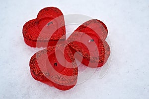 Three red hearts - candles on white snow, a gift for loved ones.