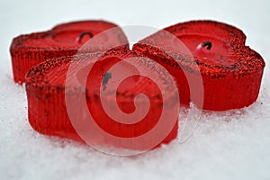 Three red hearts - candles on white snow, a gift for loved ones.