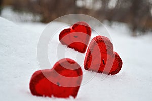 Three red hearts - candles on white snow, a gift for loved ones.