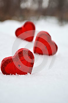 Three red hearts - candles on white snow, a gift for loved ones.