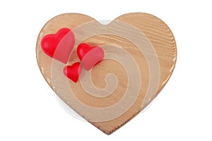 Three red hearts of different sizes on a large wooden golden heart isolated on a white background.Ð¡oncept of love, family,