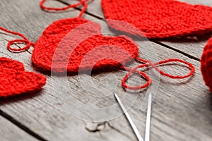 Three red knitted hearts on a gray wooden background, symbolizing love and family. Family relationship, bonds